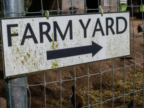 A Farmyard sign with an arrow on it